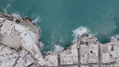 Imágenes-Aéreas-De-Arriba-Hacia-Abajo-De-La-Ciudad-De-Polignano-A-Mare-Y-Los-Acantilados-Junto-Al-Mar-Con-Las-Olas-Del-Mar-Mediterráneo-Chocando-Contra-Ellos