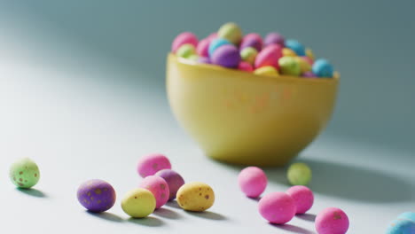 bowl with colorful easter eggs on green background with copy space