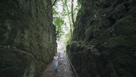 sporty female hiker walking through secret rock mountain pass