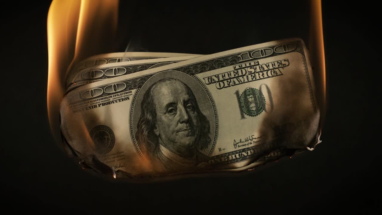 USA dollar bill money is burning in the fire, the concept of the economic crisis of inflation and currency devaluation.