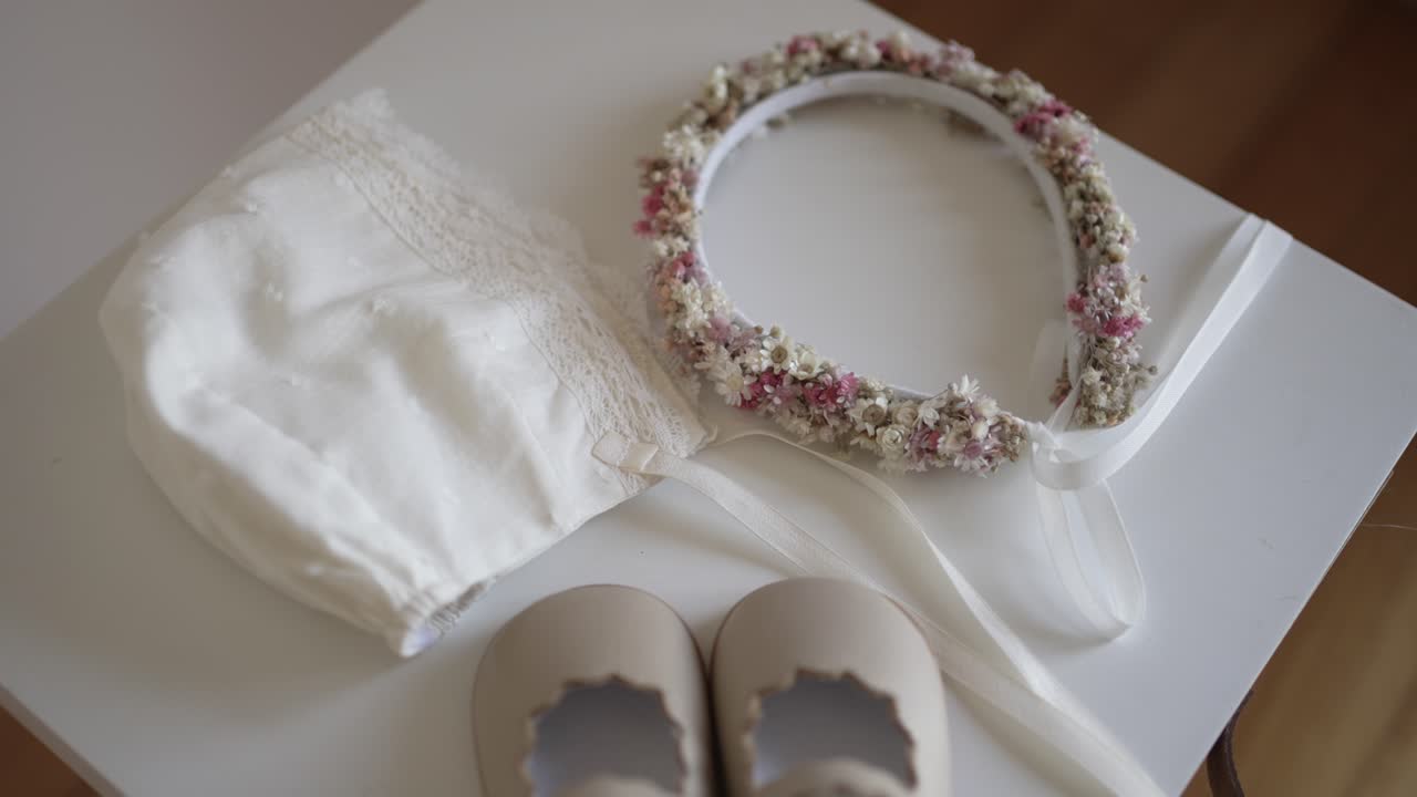 Soft baby accessories with floral crown and lace bonnet prepared for ceremony