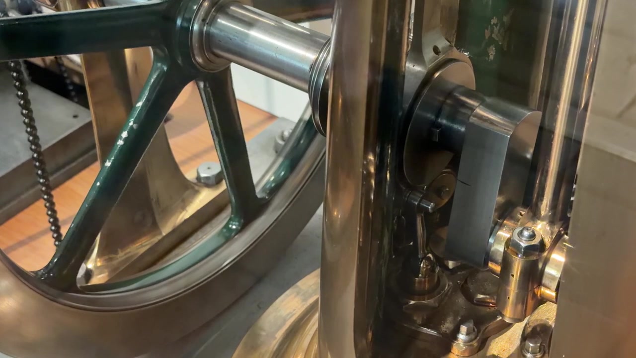 A detailed close-up shot shows the mechanical movement of a vintage brass steam engine.