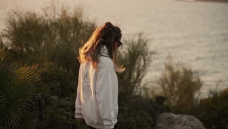 young girl walking determinedly in slow motion along a cliff with the sea in the background