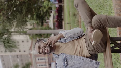 man talking on a phone while relaxing on a park bench