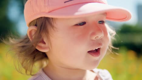 Face-close-up-of-happy-cheerful-little-girl-backlit-with-soft-sunlight-in-a-grassy-field