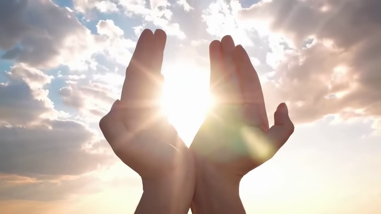 Mani che incorniciano il sole contro un cielo nuvoloso, ripreso da un'inquadratura dal basso. Ideale per un video sulla speranza.
