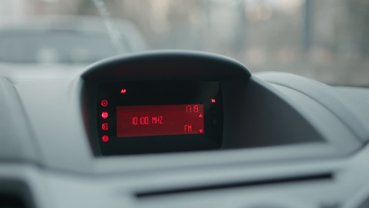 salpicadero del coche y pantalla lcd roja que muestra el reloj y busca canales de emisoras de radio fm en cámara lenta