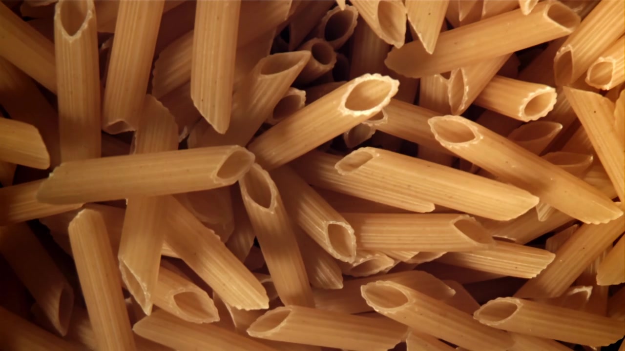 Penne secche che cadono, creando uno sfondo testurizzato.
