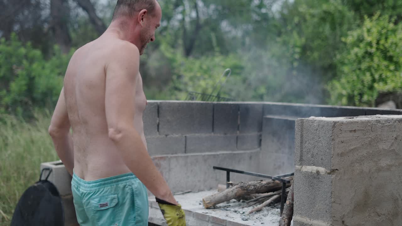 Man starting a fire in an outdoor barbecue grill