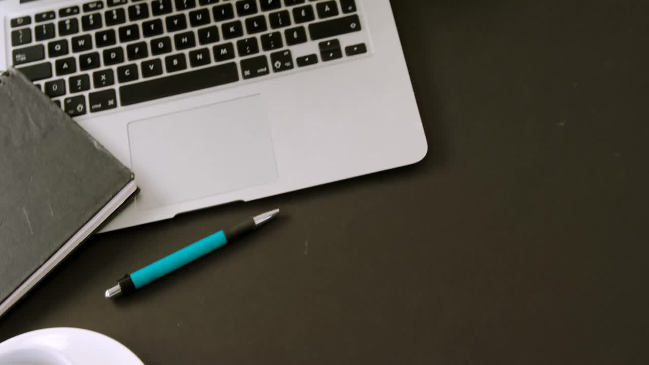 Laptop, flora, organizer, coffee and pen on black background 4k