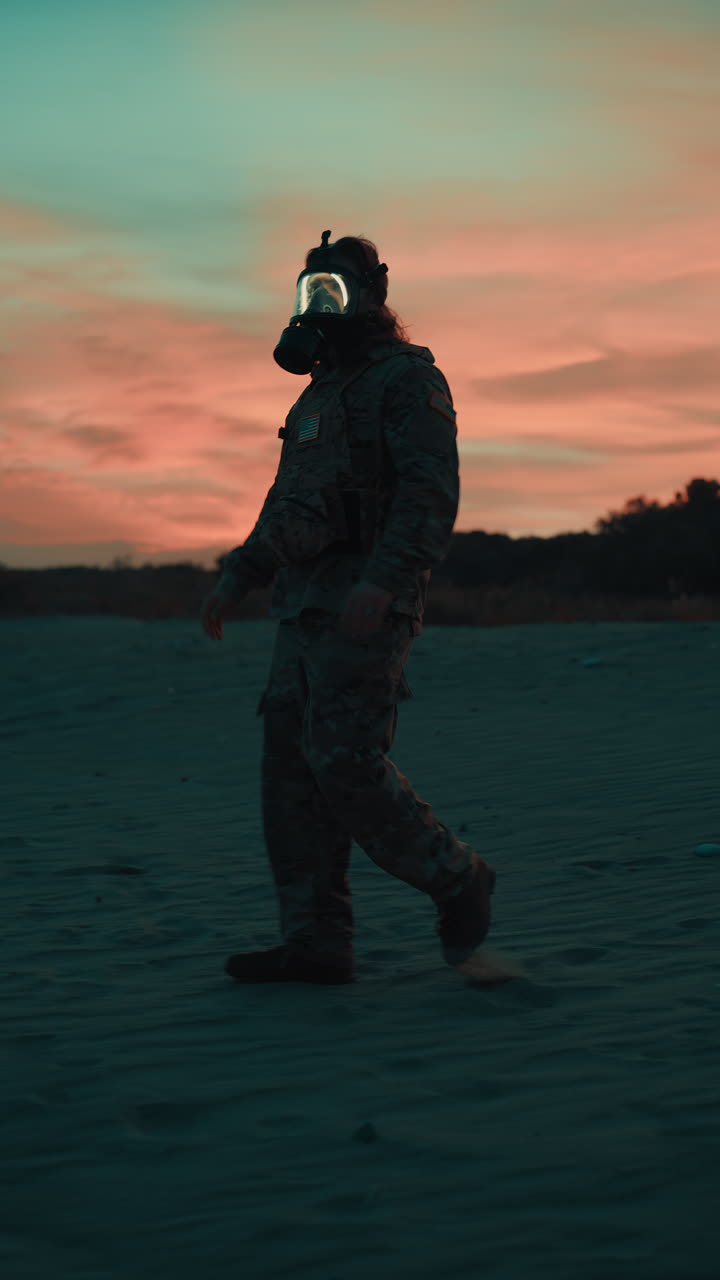 Walking on the beach Military silhouette with gas mask at red sunset