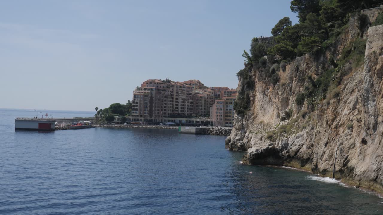 Scenic view of the rugged Mediterranean cliffs in Monaco-Ville overlooking the Fontvieille district. Luxury apartments meet the blue sea under a clear sky on the iconic Cote d'Azur