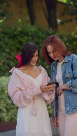 two young women looking at a smartphone outdoors