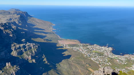 top of the world table mountain cape town south africa cliffs stunning epic morning view downtown city lions head hike fitness exercise lush spring summer grass flowers green deep blue ocean pan up