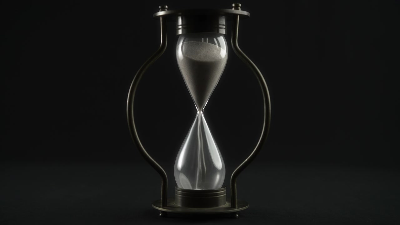 Hand Flipping an Hourglass on a Dark Background
