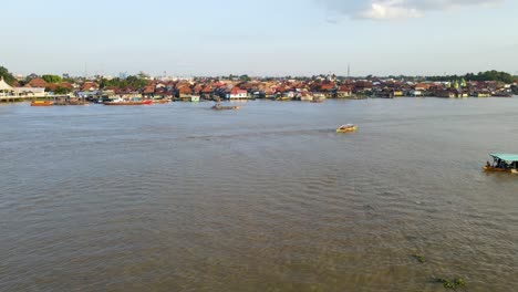 Colorful-rooftops-of-Palembang-city-while-flying-over-Musi-river-with-sailing-boats