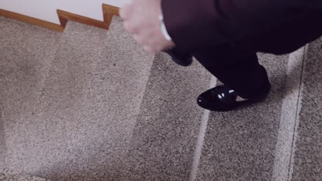 close up of a man's polished black dress shoes stepping onto a staircase, wearing formal trousers