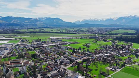 small town in switzerland between green idyllic fields in summer