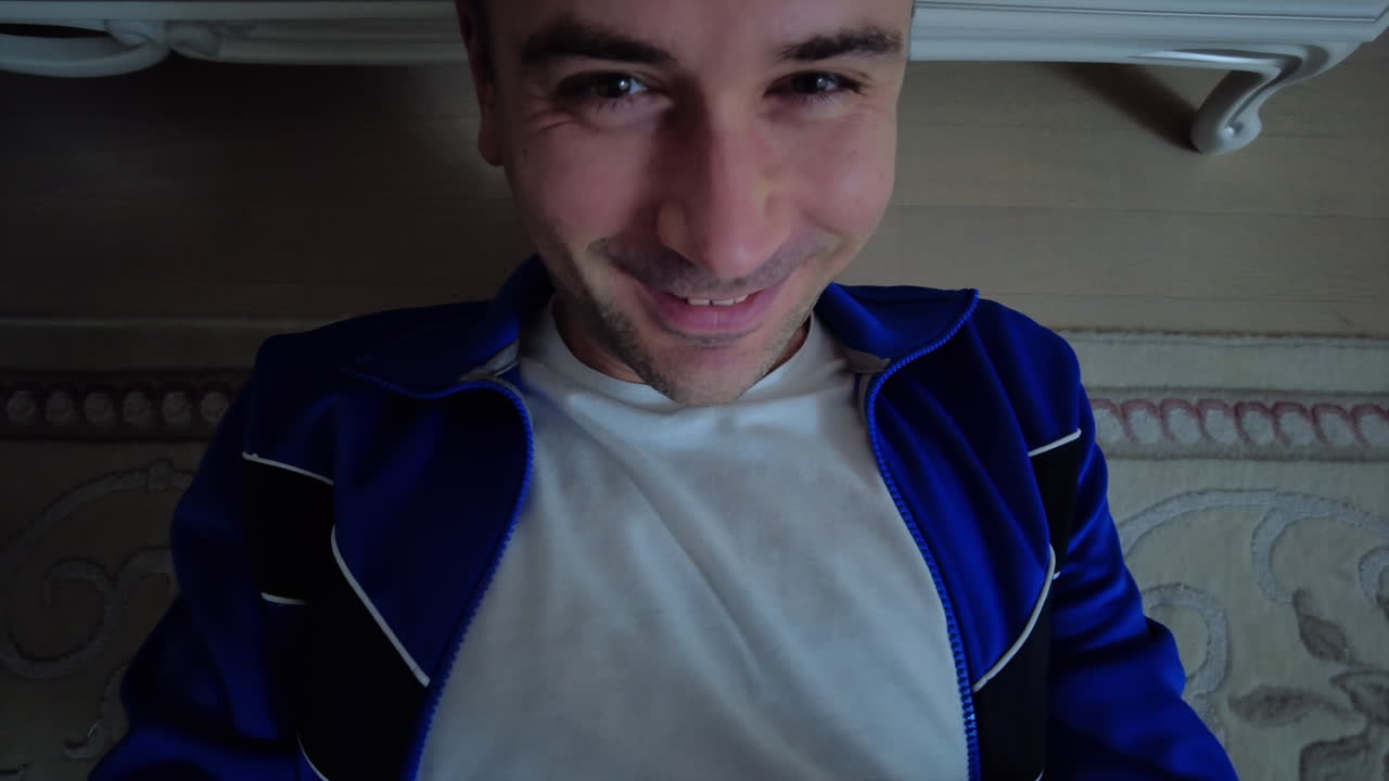 A man enjoys a quiet afternoon lying on the floor, smiling contently. The cozy atmosphere and soft lighting create a relaxed vibe