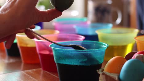 dark green easter egg is pulled from a cup of dye