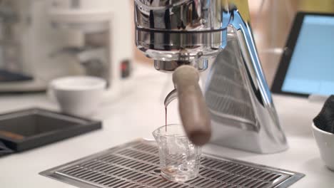 vista frontal de mano del espresso goteando de la máquina de café en el mostrador del café