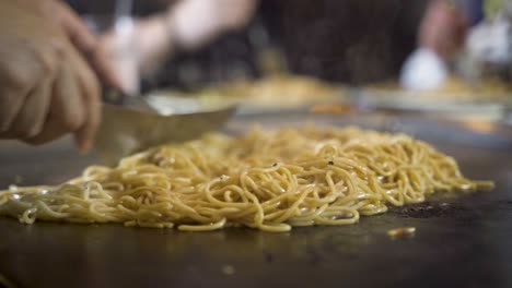 slow motion of noodles being cooked on a hot plate using kitchen utensils