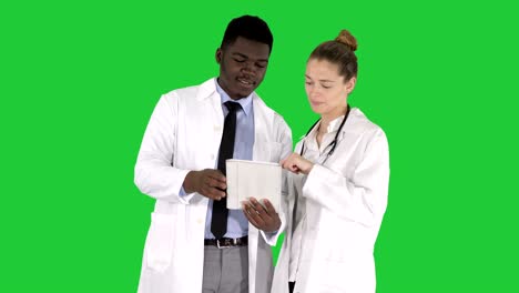 intellectual healthcare professional afro american doctor with collegue using digital tablet on a green screen, chroma key