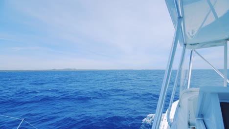 view of land in distance beyond deep blue ocean, seen from a luxury yacht