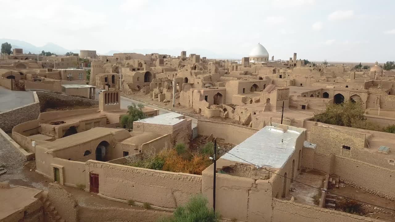 Mud brick village down town rural area adobe house buildings mosque and ruins of ancient civilization local people life in desert wide view of horizon cloudy sky summer sun in saudi arabia yazd iran