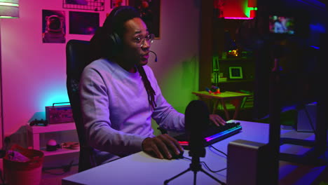 man playing video games in his bedroom at night