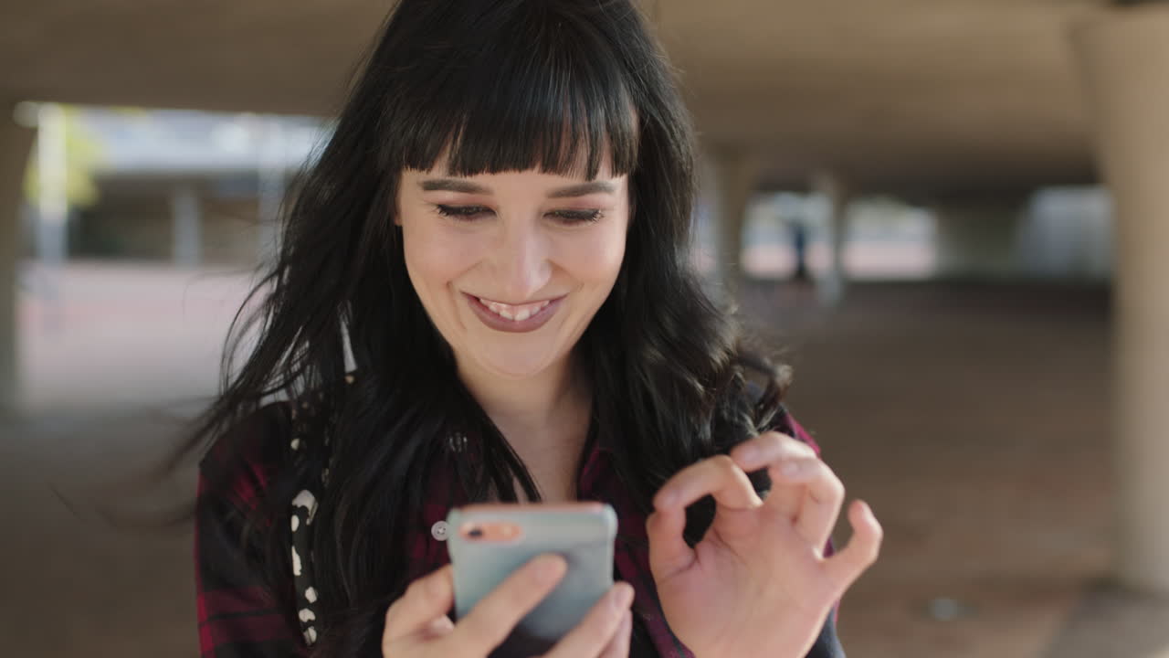 retrato de una hermosa mujer independiente y de moda sonriendo usando un teléfono inteligente de fondo urbano
