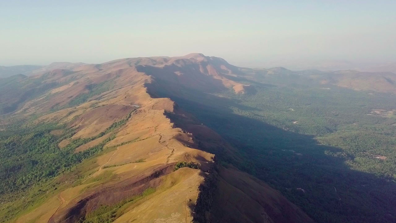 Catena montuosa di Chikmagalur con ampie valli verdi sotto cieli sereni, ripresa con vista aerea.