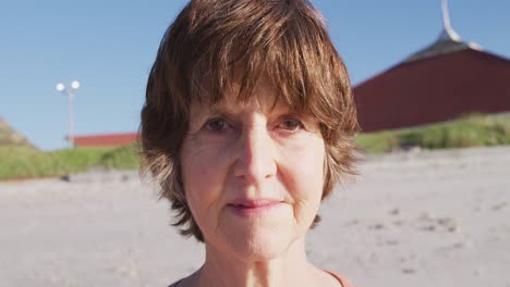 Mujer-Caucásica-Mirando-La-Cámara-Y-Sonriendo-En-La-Playa-Y-El-Fondo-Del-Cielo-Azul