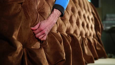 upholsterer working on a tufted sofa