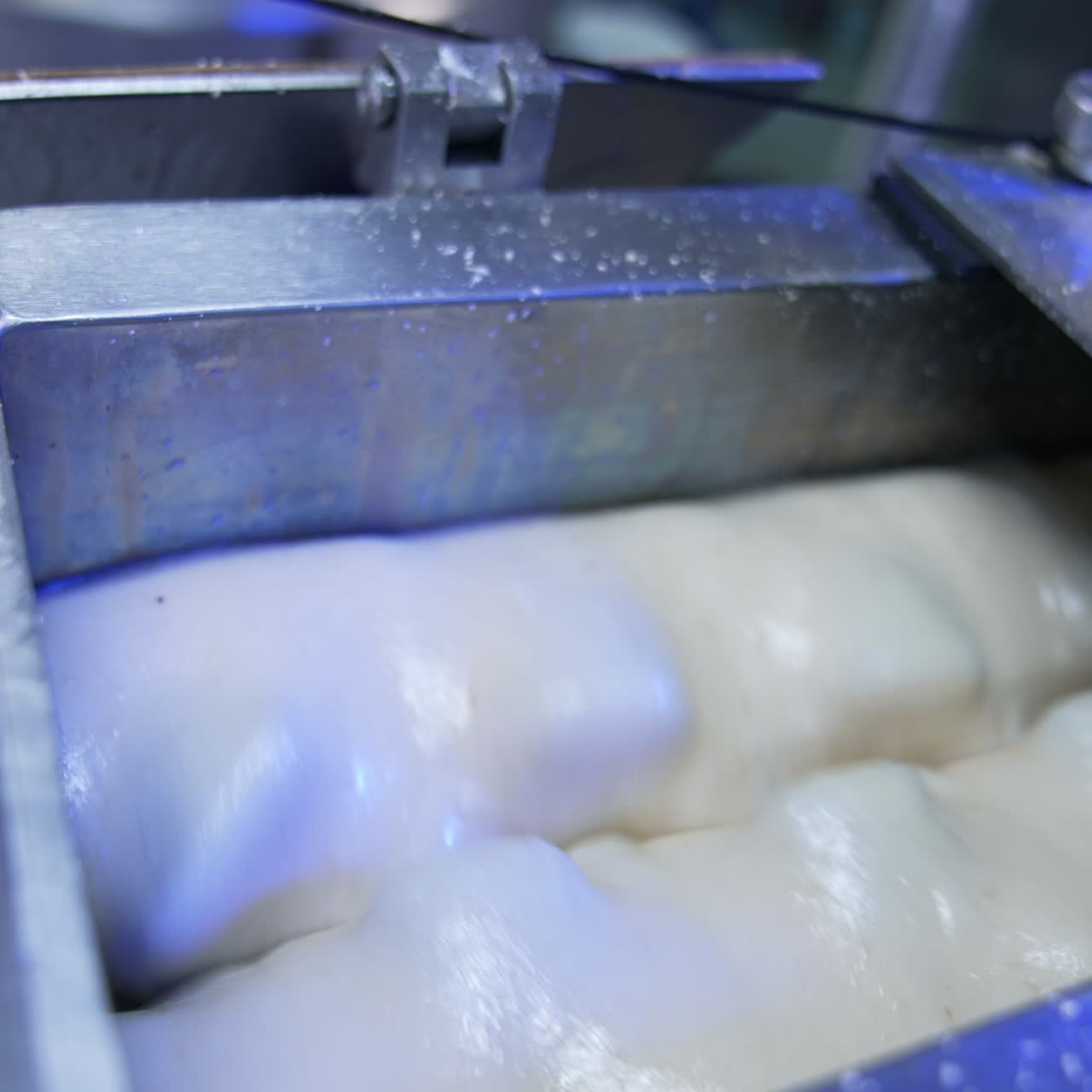 Milky creamy substance being rotated in the metal tank. Sweet products manufacturing at modern food factory. Close up