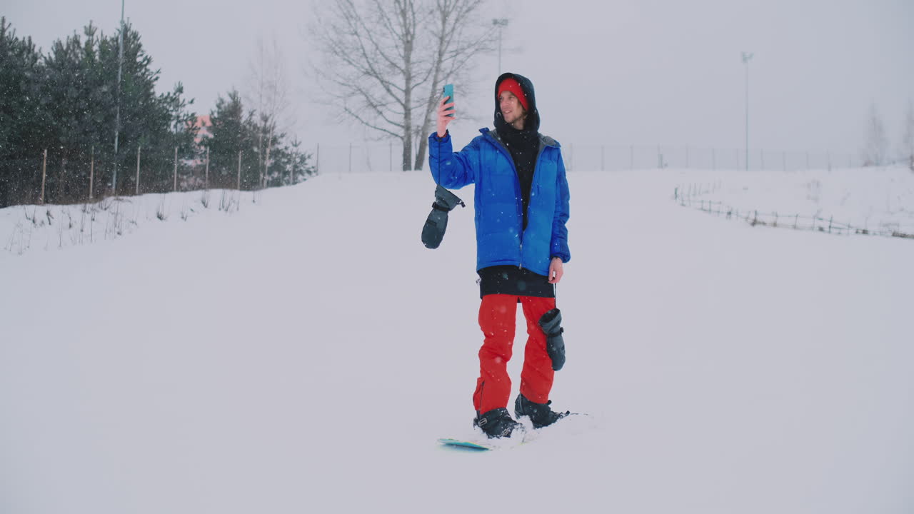 스키장에서 스노보드를 타면서 스마트폰으로 풍경 사진을 찍으세요.