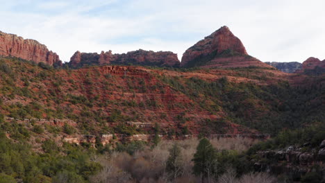 aerial: mountain valley with woodland forest at sedona, arizona - establishing drone flying forward shot