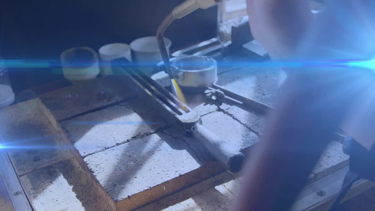 火炬從右側進入，珠寶匠正在加熱固定在工作台上的金屬，熔化焊料並連接部件