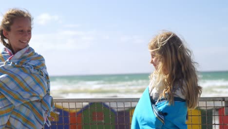 siblings standing with towels near beach 4k