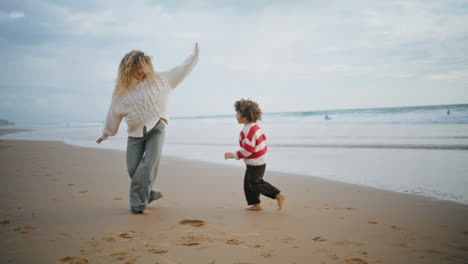 Lindo-Hijo-Corriendo-Madre-En-La-Playa-De-Otoño.-Niñera-Feliz-Abrazando-A-Un-Niño