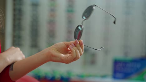 woman at optician with glasses. close up of woman hand holding sunglasses