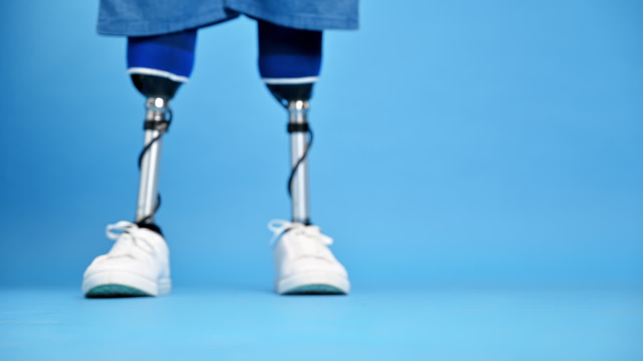 View of a man with prosthetic legs and white sneakers making a step, blue background