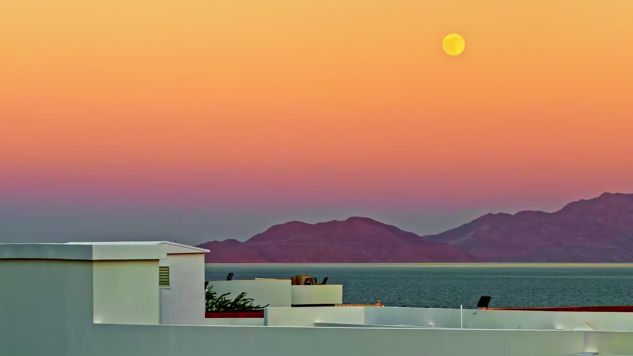 Moonrise over Sharm El Sheikh rooftops, peaceful evening sky scenery