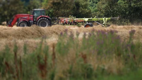 a tractor aerating cut grass on a farm field in rural denmark