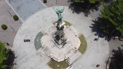 Flock-of-pigeons-fly-past-angel-statue-in-Liberty-Plaza,-San-Salvador