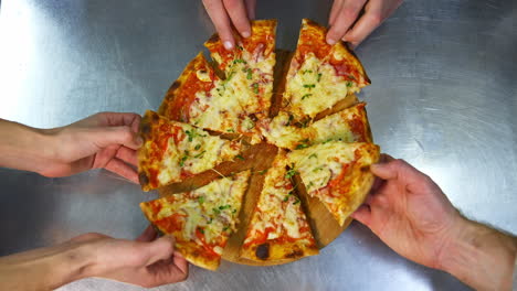 hands taking slices of pizza. hands taking pizza slices from wooden plate