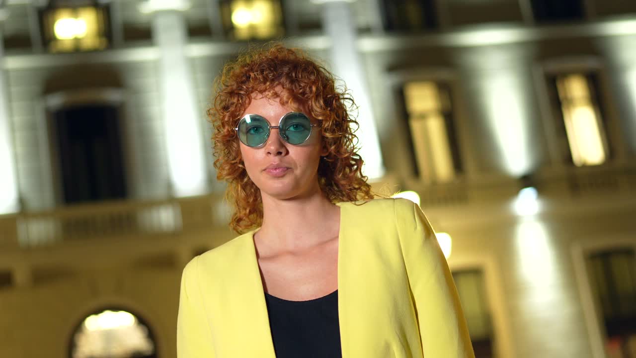 Woman with Curly Hair and Sunglasses in Urban Night Setting