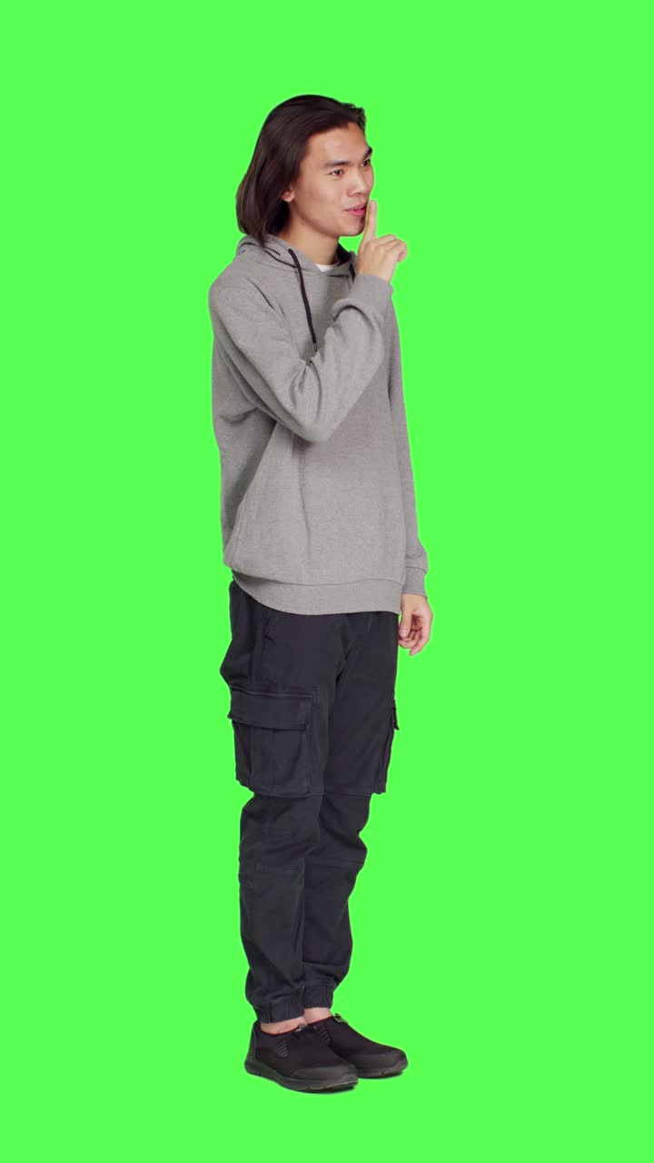 Side view of adult doing hush sign over greenscreen