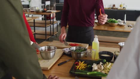 Caucasian-female-chef-teaching-diverse-group-wearing-face-masks