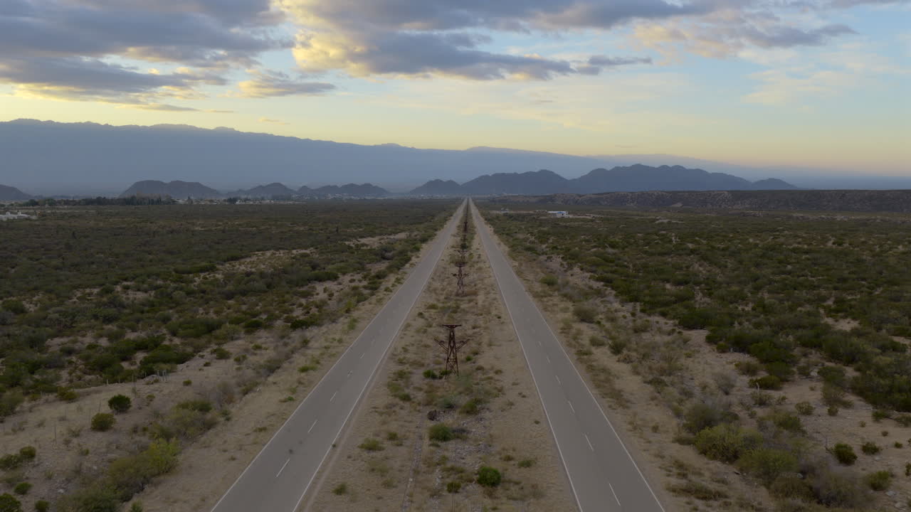 Av. la Mexicana, Chilecito, La Rioja, Argentina. Straight, endless highway across arid valley with mountains on horizon